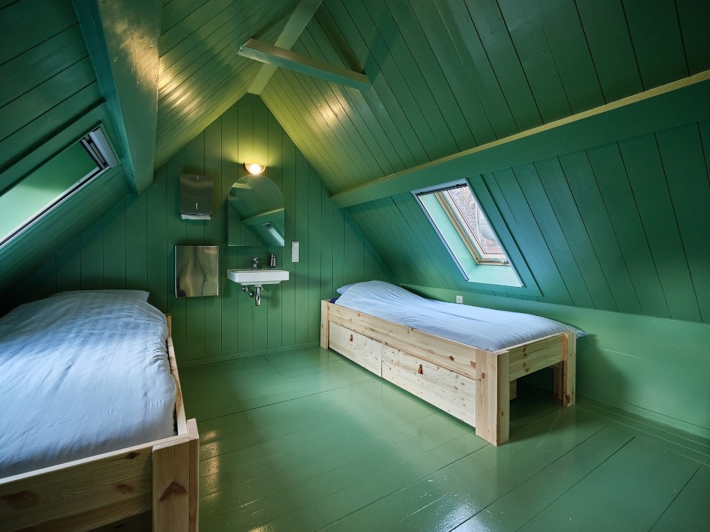 Zolderkamer met dakramen en houten bedden in Het Molenhuis