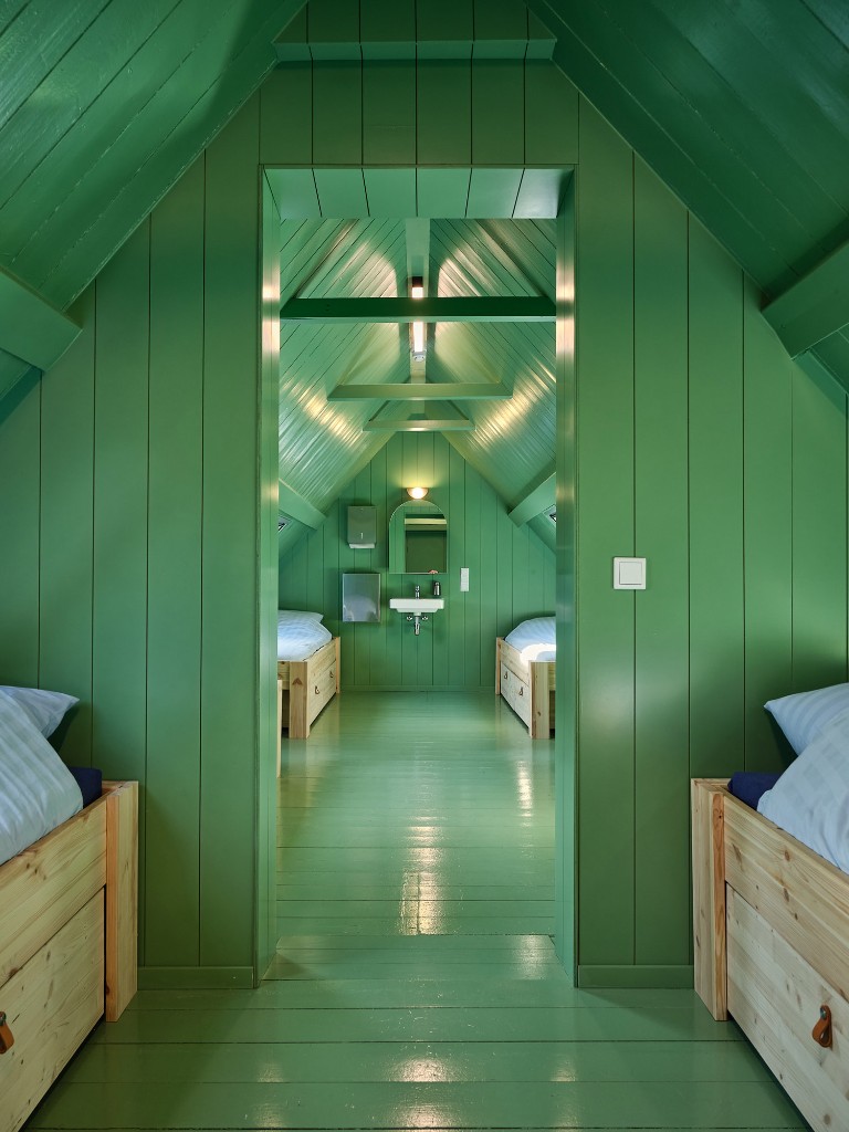 Groene slaapkamer met houten bedden en wastafel in Het Molenhuis