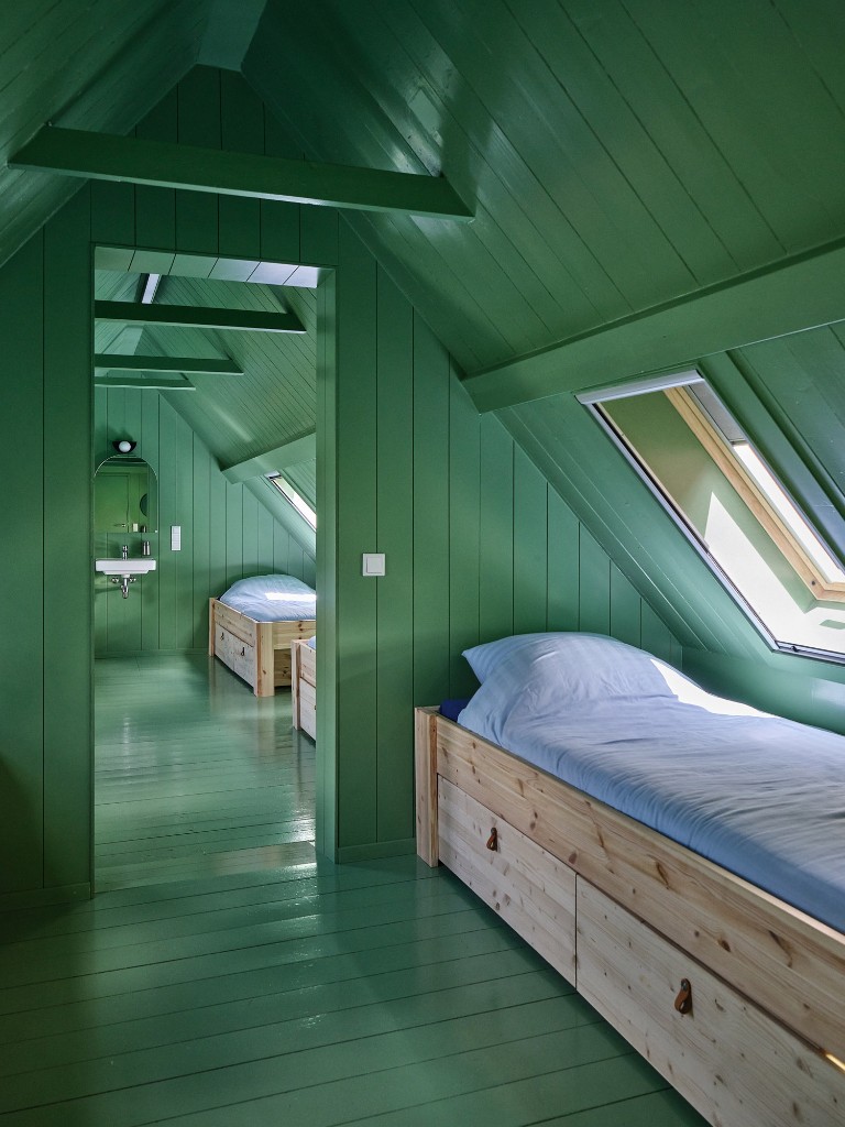 Groene zolderkamer met houten bedden en dakramen in Het Molenhuis