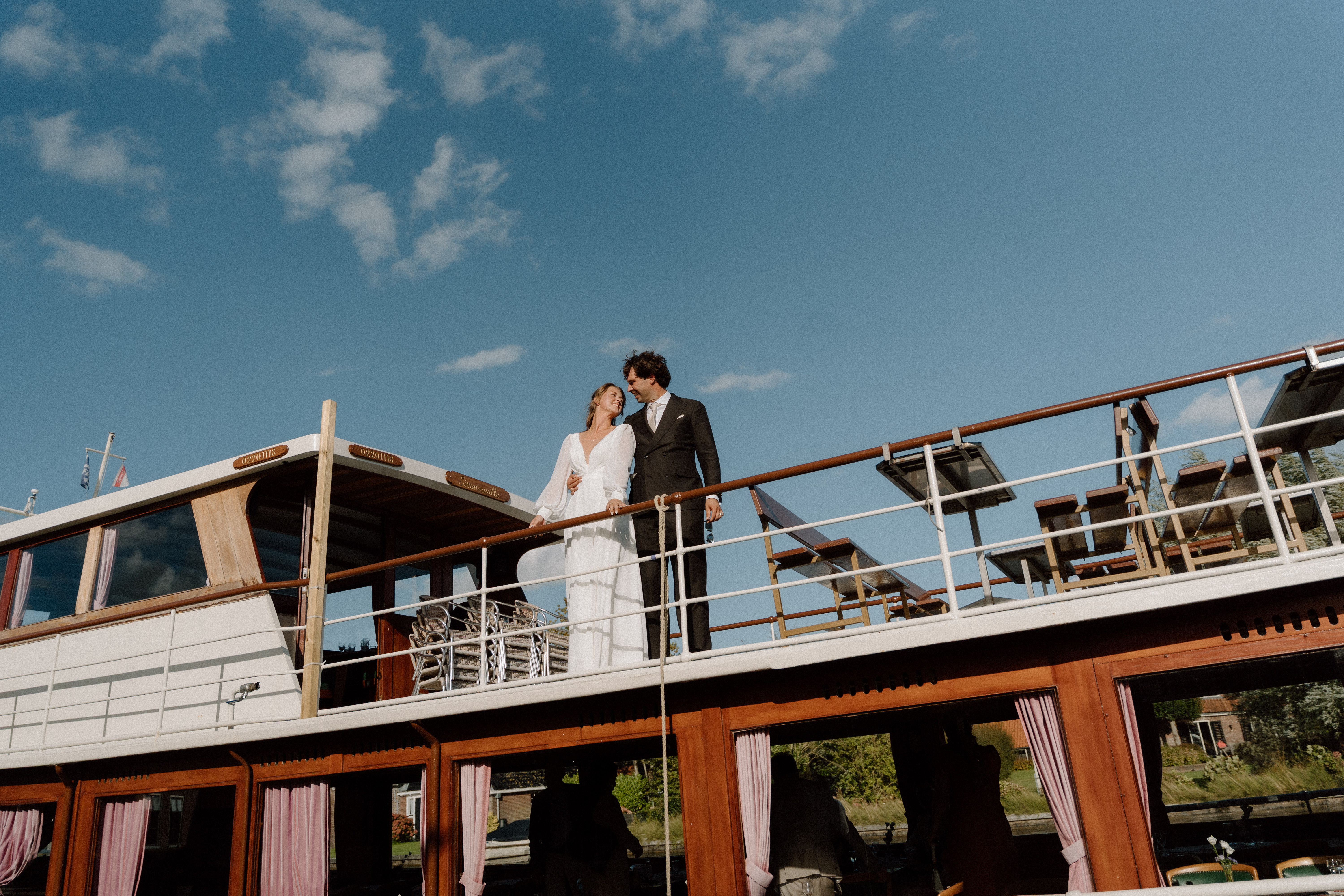 Bruidspaar op het dek van de salonboot tijdens een trouwweekend bij Het Molenhuis