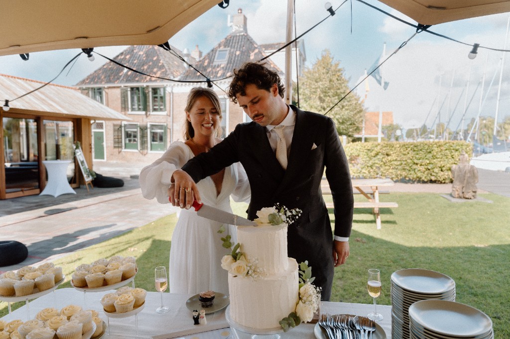Bruidspaar snijdt de taart aan onder de stretchtent bij Het Molenhuis